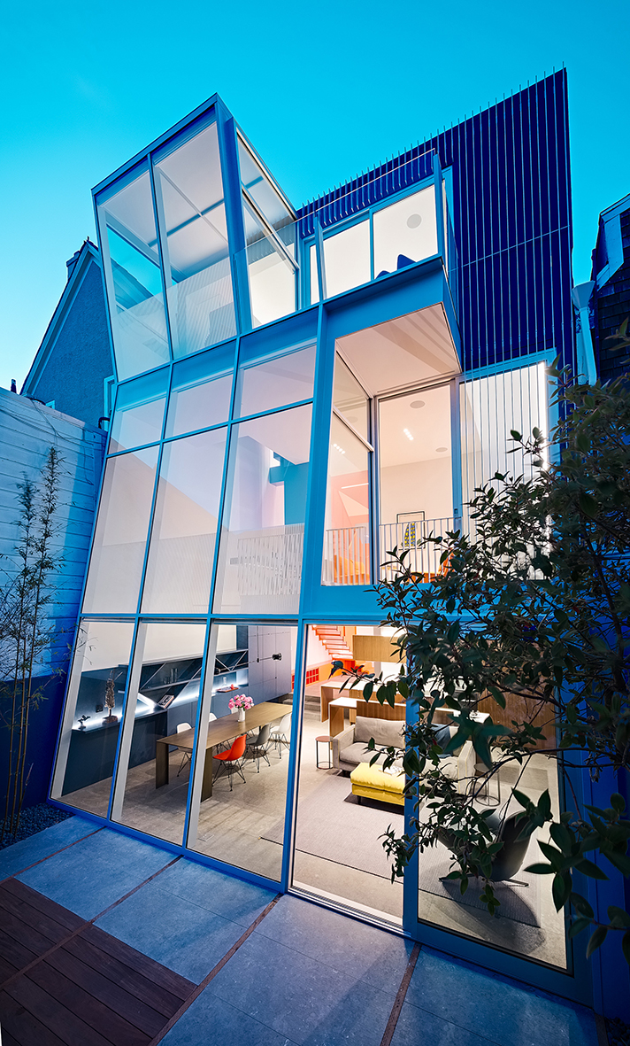 Multi-level home with angled glass windows bathed in blue light