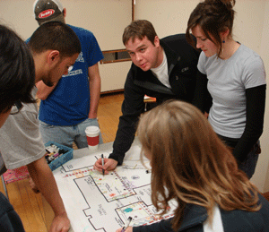 Photo of group of students clustered around a plan, working together