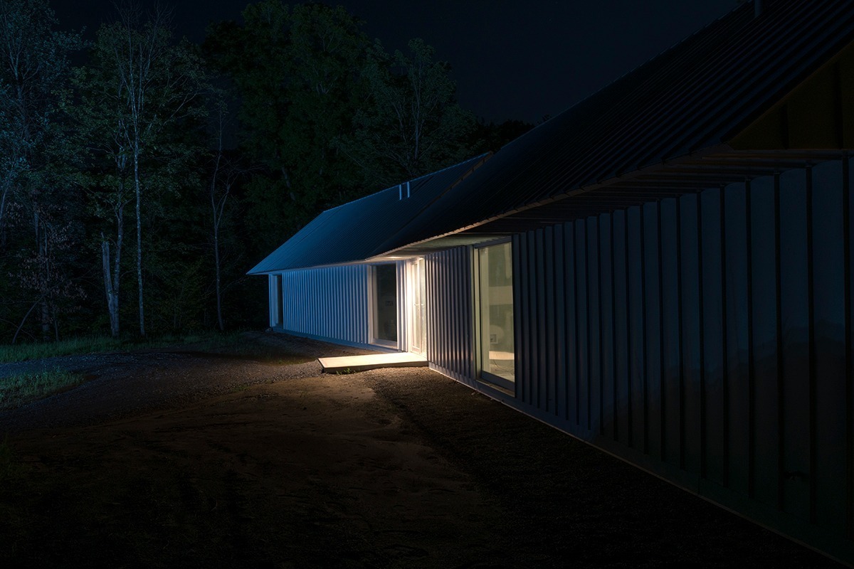 Exterior shot of white home lit from within at night 