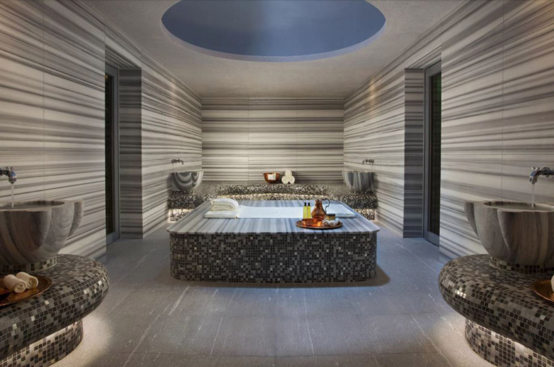 Black and gray mosaic tiles, and gray-striped walls create a relaxing spa atmosphere.