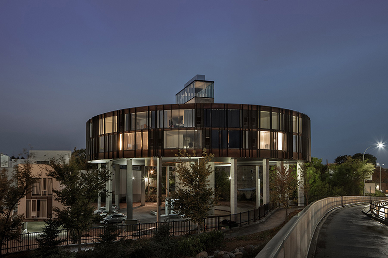 Exterior shot of dark, circular building covered with windows at night. 