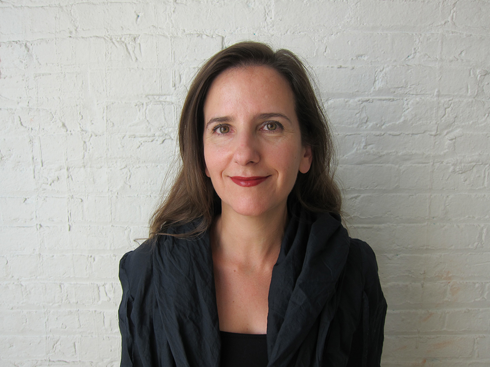 Georgeen Theodore standing against a white brick wall